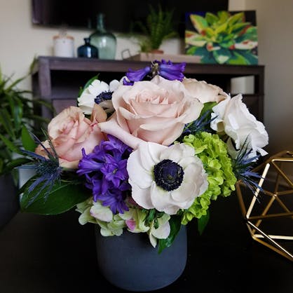 A small potted bouquet of purple, green and pink tones
